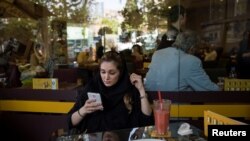 Iran -- An Iranian woman uses her mobile phone to follow election news in a coffee shop in Tehran, Iran May 17, 2017. 