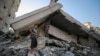 Un băiat și un bărbat palestinian inspectând distrugerile în sud-vestul orașului Gaza, o zonă lovită de tirurile israeliene, pe 29 august 2025.