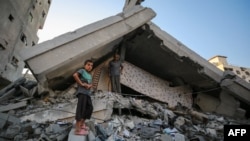 Un băiat și un bărbat palestinian inspectând distrugerile în sud-vestul orașului Gaza, o zonă lovită de tirurile israeliene, pe 29 august 2025.