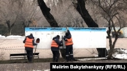 Көшедегі жарнама ілетін тақтаны жөнге келтіріп жатқан жұмысшылар. Алматы, 15 ақпан, 2026 жыл.