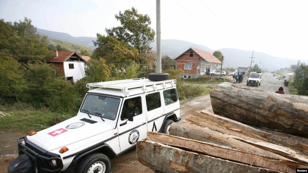 A NATO KFOR vehicle passes by a partially removed roadblock near the village of Zupce in the tense northern Kosovo region. 