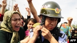 Uyghur women surround a Chinese riot policemen as they protest in Urumqi on July 7.