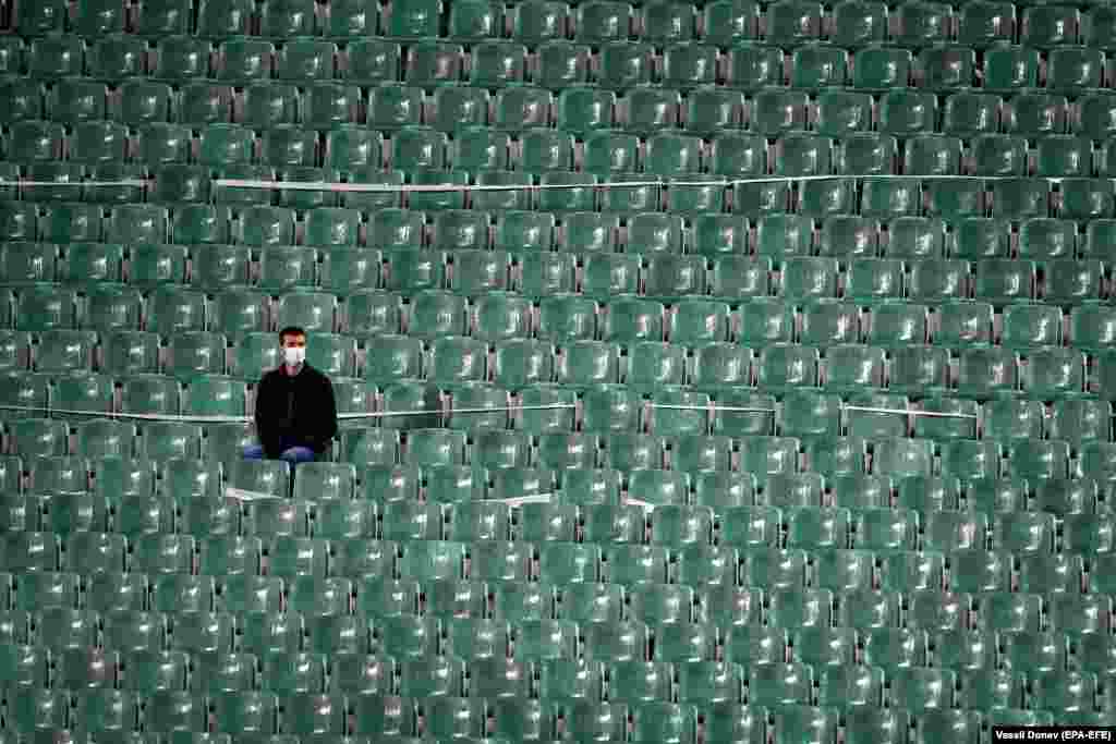 A soccer fan, wearing a protective face mask in a deserted stand, watches a Euro 2020 qualifying game between Bulgaria and Hungary in Sofia on October 8. (epa-EFE/Vassil Donev)