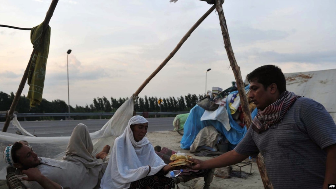 A Pakistani commuter offers bread to flood survivors on a roadside in Charsadda, Pakistan on August 12.