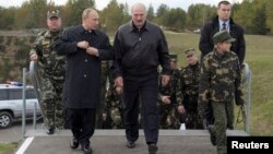 Russian President Vladimir Putin (left, front) and Belarusian counterpart Aleksandr Lukashenka (center, front), with Lukashenka's son alongside them, visit the joint war games Zapad-2013 at the Gozhsky firing range in Grodno on September 26.