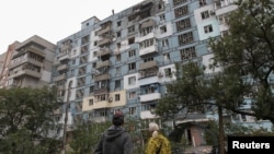Locuitorii privesc un bloc de apartamente lovit de un atac cu drone rusești, pe fondul atacului Rusiei asupra Ucrainei, la Dnipro, Ucraina, 11 octombrie 2026.