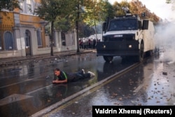 Një person qëndron i shtrirë në rrugë teksa prapa tij shihet kamioni që lëshon ujë drejt protestuesve në Tiranë më 24 tetor.