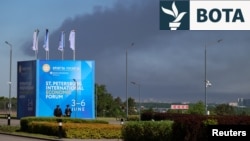 Shtëllunga tymi në Shën Petersburg më 3 qershor, teksa shihet edhe bilbordi që njofton për mbajtjen e Forumit Ekonomik në këtë qytet rus. 
