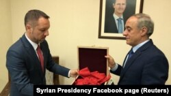 Фото, опубликованное на странице президента Сирии в Facebook'е, в подписи к которому говорится, что представитель МИД Сирии передал знак врученного Францией ордена посольству Румынии в Дамаске. 19 апреля 2018 года.
