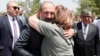 In a photo made available by the government, Armenian Prime Minister Nikol Pashinian is hugged by a woman at a burial place, on the outskirts of Yerevan, of Armenian soldiers killed during the Nagorno-Karabakh conflict.