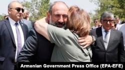 In a photo made available by the government, Armenian Prime Minister Nikol Pashinian is hugged by a woman at a burial place, on the outskirts of Yerevan, of Armenian soldiers killed during the Nagorno-Karabakh conflict.