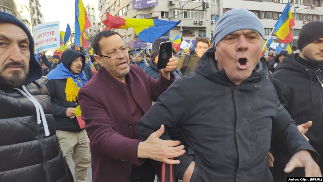 Un bărbat încearcă să liniștească un manifestant care huiduie o echipă de jurnaliști la protestul AUR, pe 12 ianuarie 2025.
