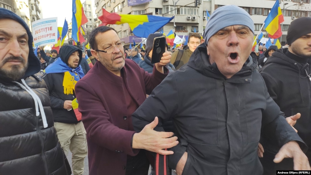 Un bărbat încearcă să liniștească un manifestant care huiduie o echipă de jurnaliști la protestul AUR, pe 12 ianuarie 2025.