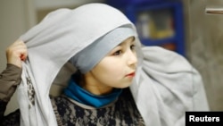 Sanaa, 10 ani, își pune hijab-ul înainte de a intra la Scoala Islamică de Sâmbătă, Leyton, estul Londrei, 9 noiembrie 2013. Mama ei spunea atunci că de la 11 ani Sanna va trebui să poarte obligatoriu zilnic hijab-ul, dar doar dacă asta va fi alegerea ei. 