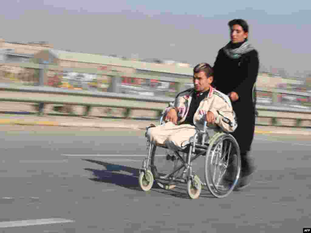 A handicapped Shi'ite pilgrim is pushed on a wheelchair on a highway linking Baghdad to Karbala on January 20 as Shi'ite Muslim pilgrims continued to walk toward the central shrine city where they will attend next week the upcoming Arbain religious festival. Photo by Ahmad al-Rubaye for AFP