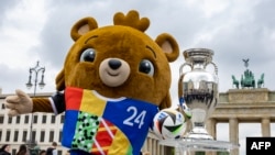 Ariu Albaert, maskota e Euro 2024, duke pozuar me trofeun e Kampionatit Evropian të futbollit, para Portës së Brandenburgut, në Berlin, Gjermani, më 24 prill 2024.