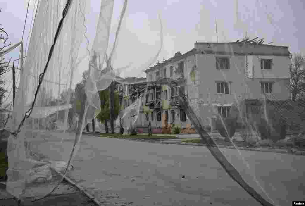 Stambena zgrada oštećena ruskim zračnim napadima i antidron mreža postavljena na ulici ispred, u gradiću Orihiv u Zaporoškoj oblasti. 13. novembar 2025.