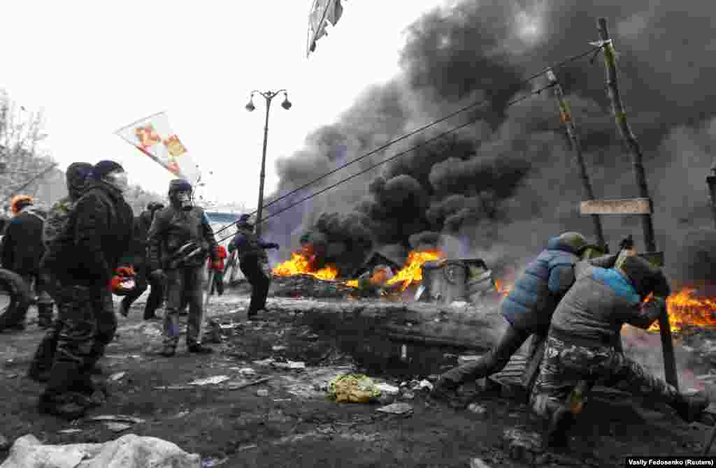 Protesters use a giant slingshot to aim projectiles at riot police.