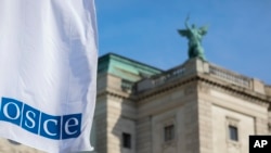 Развевающийся на ветру флаг ОБСЕ перед входом в здание, где заседает Постоянный совет Организации по безопасности и сотрудничеству в Европе в Вене, Австрия.