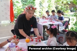 Українська волонтерка Світлана Дзюма-Чан плете з дітьми вінки. Пекін, Китай, 4 травня 2025 року