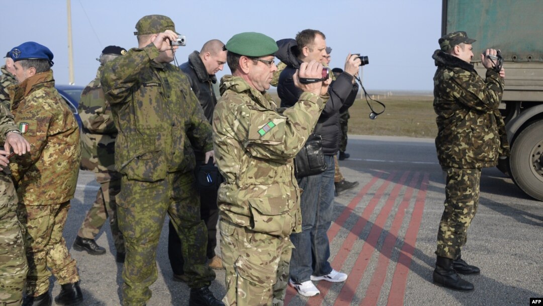 OSCE military observers take photos during negotiations with pro-Russian forces at a checkpoint blocking the entrance to Crimea last month.