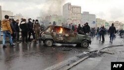 Iranian protesters gather around a burning car during a demonstration against an increase in gasoline prices in the capital Tehran, on November 16, 2019.