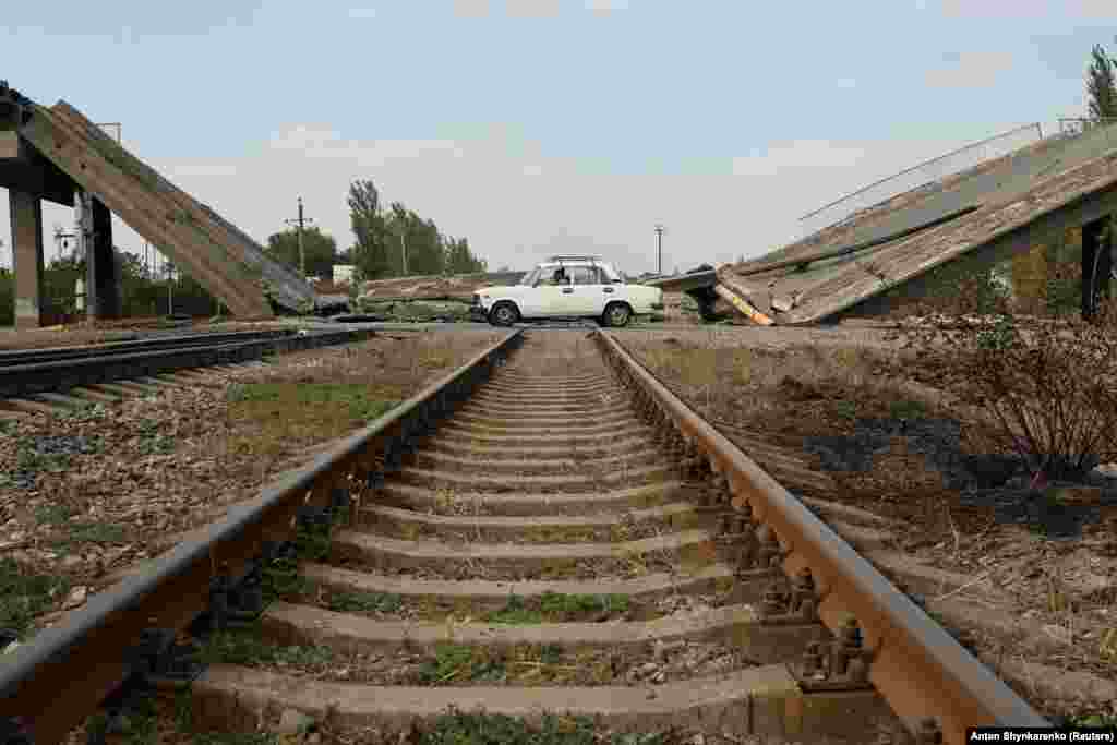 A car drives past a destroyed bridge in the town of Pokrovsk in Ukraine&#39;s eastern Donetsk region.