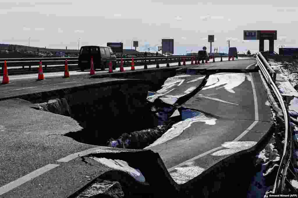 A car drives past a collapsed road near the village of Mazgi, two weeks after heavy rain brought devastating floods to western Kosovo. (AFP/Armend Nimani)