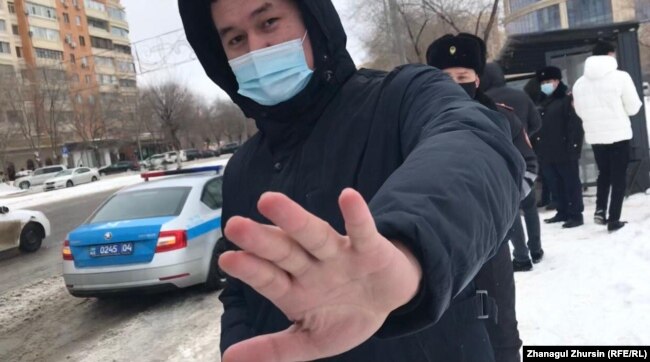 Мужчина в темной одежде и в маске препятствовал корреспонденту Азаттыка освещать акцию протеста. Актобе, 28 февраля 2021 года.