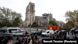 Notre Dame baş ybadathanasynda dörän ýangyn söndürilenden soňra adamlar ony synlaýarlar we surata düşürýärler.