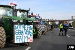 Traktorët e bujqve francezë, përfshirë një me mbishkrimin: “Fundi ynë nënkupton krizë urie për ju”, ta parkuar në autostradën A4 në lindje të Parisit, 29 janar 2024, gjatë protestës së bujqve për rregulloren, taksat dhe pagesat.