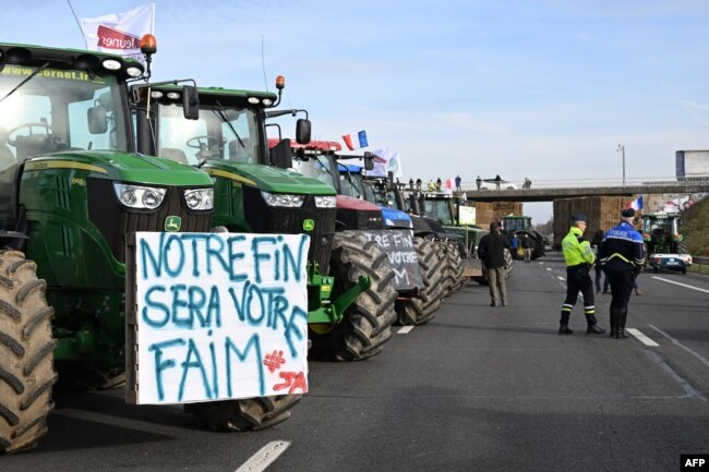 Traktorët e bujqve francezë, përfshirë një me mbishkrimin: “Fundi ynë nënkupton krizë urie për ju”, ta parkuar në autostradën A4 në lindje të Parisit, 29 janar 2024, gjatë protestës së bujqve për rregulloren, taksat dhe pagesat.