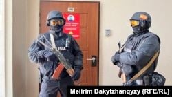 Халықаралық құқық қорғау ұйымдарынан тұратын коалиция Қазақстан билігін "журналистерге қарсы қысымды" доғаруға шақырды. Суретте Orda.kz басылымының Алматыдағы кеңсесін тінту кезінде есік сыртында күзетіп тұрған құзырлы орган қызметкерлері. 1 желтоқсан 2025 жыл