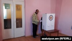 A person helping an elderly woman to vote in Armenian local elections last year.