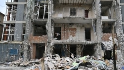A resident of a Kyiv apartment building clears debris following a Russian drone strike on May 25.
