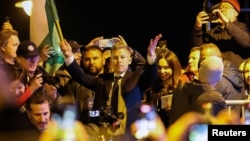Lider Tise Peter Mađar drži mađarsku zastavu dok slavi, nakon što je mađarski premijer Viktor Orban priznao poraz na parlamentarnim izborima, u Budimpešti, 12. aprila 2026.