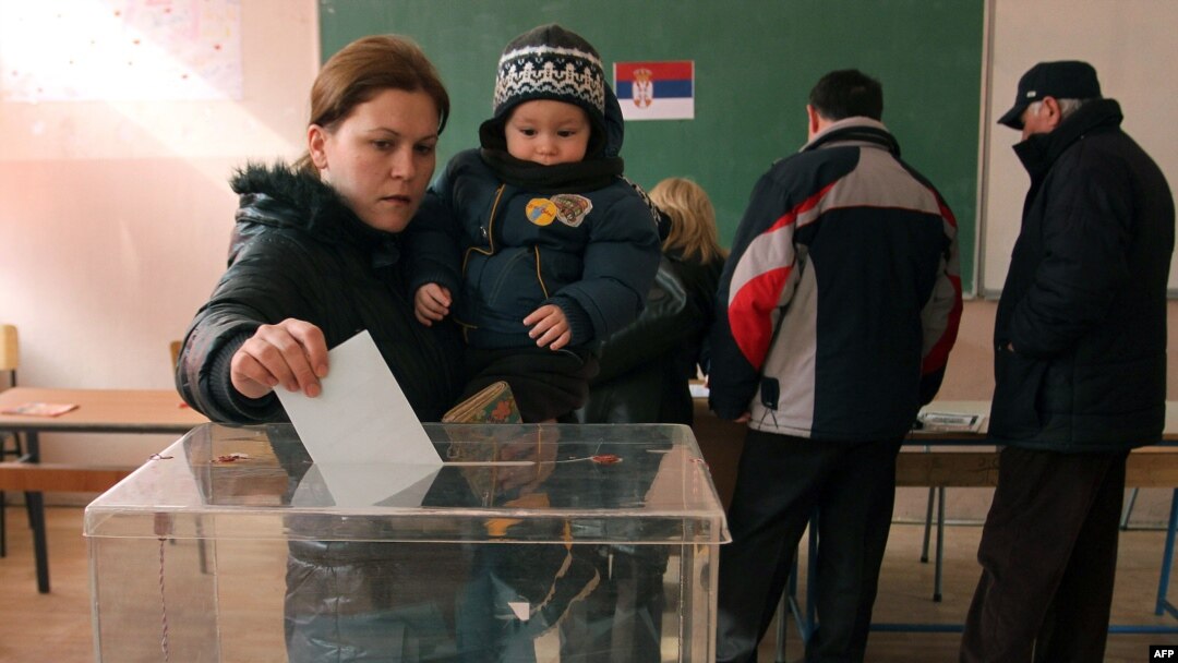 A Kosovar Serb woman with her child casts her ballot at a polling station in Kosovska Mitrovica.