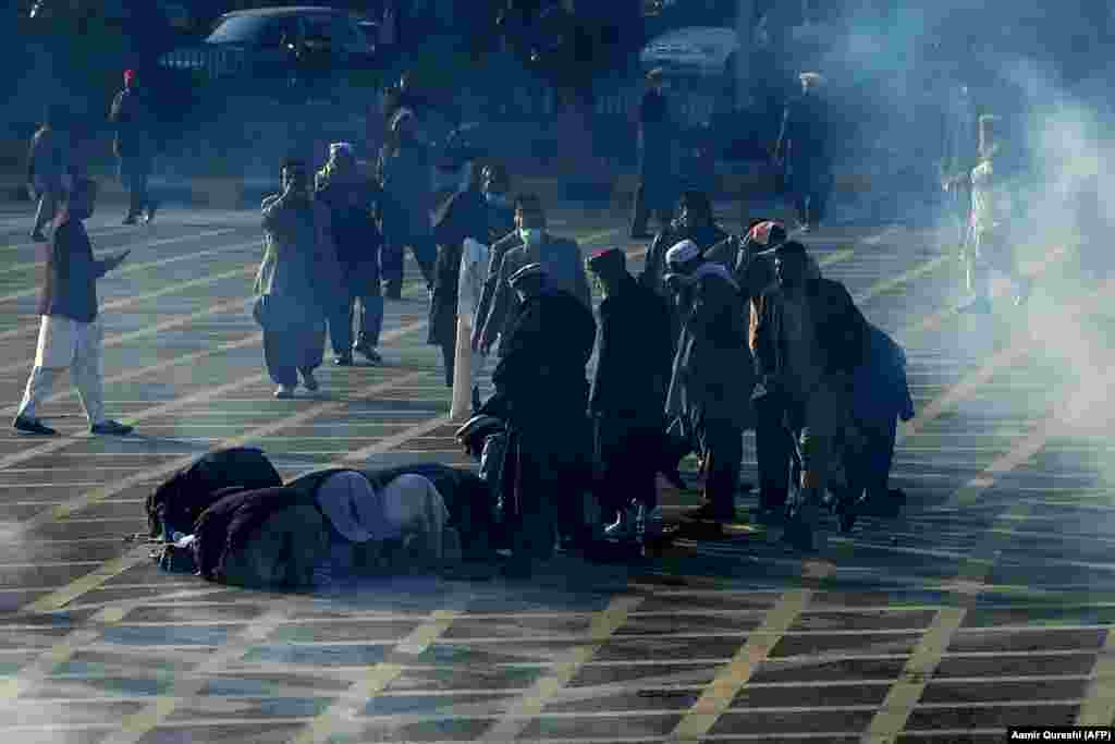 Пакистанские правительственные служащие молятся на улице во время запуска полицией слезоточивого газа. Митингующие идут к парламенту во время акции протеста с требованием повышения заработной платы в Исламабаде, 10 февраля