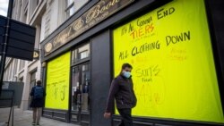 Мужчина в маске идет мимо витрин закрытых магазинов в Лондоне.