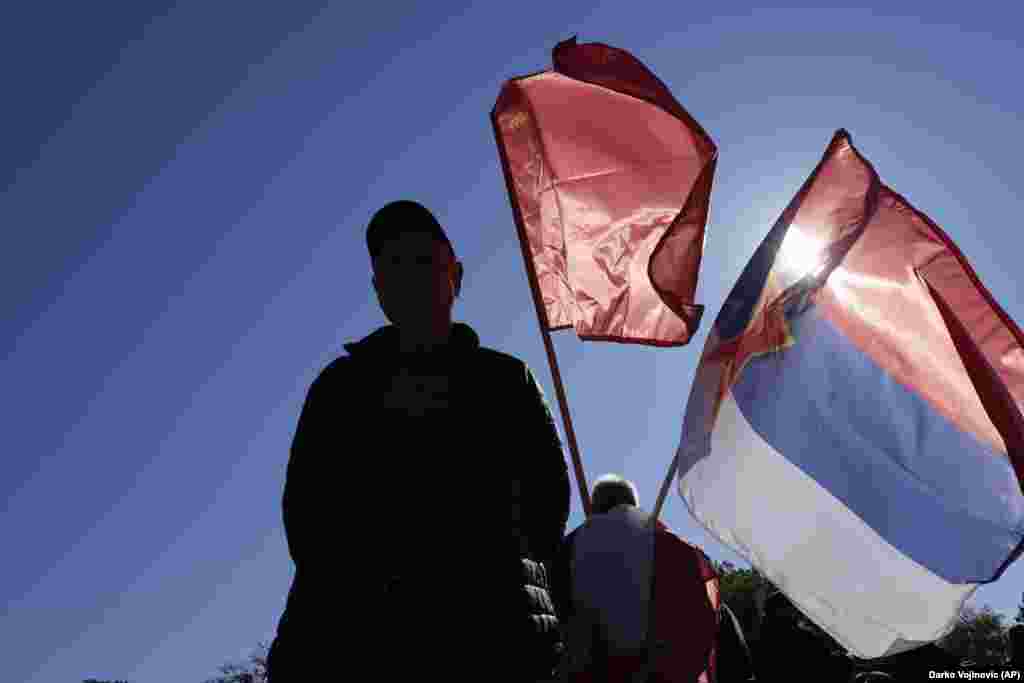 A man holds an old Yugoslav communist flag (top) and an old Serbian flag with the communist five-point star during a ceremony on the occasion of the 80th anniversary of the liberation of Belgrade from Nazi occupation in World War II by Soviet and local communist fighters, in Belgrade on October 20.