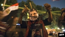 A man wearing a mask of ousted President Muhammad Morsi shows his handcuffed hands outside the presidential palace in Cairo on July 19, while Morsi opponents gather to mark the 40th anniversary of the Six-Day War against Israel.