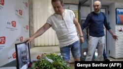 Arkady Babchenko (right) reacts as he arrives in the offices of ATR TV, where his colleagues laid flowers by a portrait of him in his memory, in Kyiv on May 31.