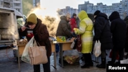 Residents receive food donations in a neighborhood with electricity and heating outages following recent Russian attacks on Ukraine’s civilian infrastructure during subzero temperatures in Kyiv.