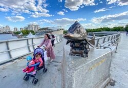 Коронавирус пандемиясы кезінде көшеде балалармен серуендеп жүрген әйел. Нұр-Сұлтан, 6 маусым 2020 жыл.