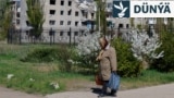 Bir aýal Russiýanyň Ukraina uran zarbalary netijesinde weýran bolan jaýyň öňünden ýöräp barýar (arhiw suraty)