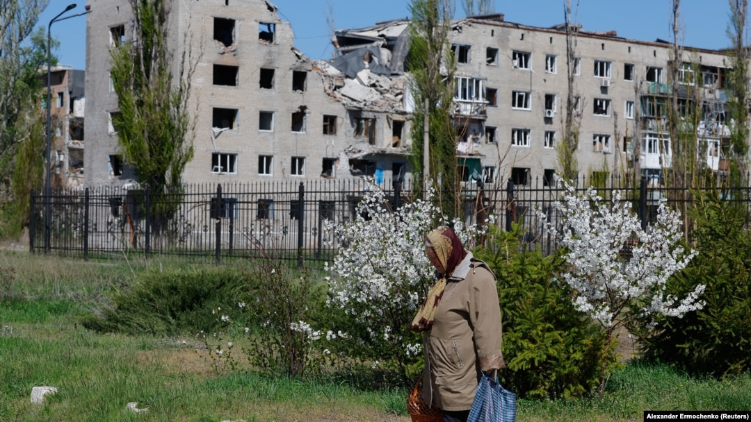 O femeie se întoarce de la biserică, după slujba de Paște, prin apropierea unui bloc distrus, în Avdiivka, în regiunea Donețk, o zonă a Ucrainei controlată de Rusia, 20 aprilie 2025.