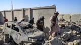 Taliban security personnel walk past a damaged car in Kandahar province on October 16,.