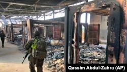 U.S. soldiers on January 13 walk past the site of where Iran bombed the Ain Al-Asad air base in Iraq. 