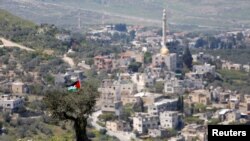 Një flamur palestinez i varur në një pemë gjatë një proteste kundër vendbanimeve izraelite në një fshat të Bregut të uzurpuar Perëndimor, 29 mars 2021.