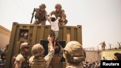Coalition forces assist a child during an evacuation at Hamid Karzai International Airport in Kabul.